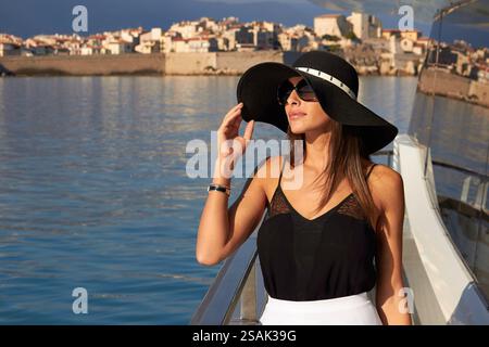Femme élégante profitant de la vue sur l'océan du yacht de luxe par la côte dans le soleil du soir Banque D'Images