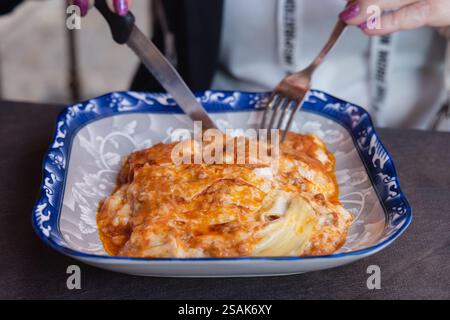 Couper de la nourriture de lasagne sur une assiette en vue rapprochée. Banque D'Images