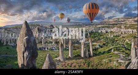 Montgolfières survolant les spectaculaires formations rocheuses de renommée mondiale de la 'Love Valley' au lever du soleil, près de Goreme, Cappadoce, Turquie. Banque D'Images