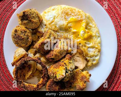 Vue au niveau des yeux sur l'assiette brunch rustique à base d'œufs frits et de légumes frits Banque D'Images