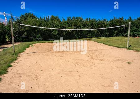 Un filet de volley-ball est installé dans un champ avec un ciel bleu en arrière-plan. Le filet est blanc et est tendu à travers le champ Banque D'Images