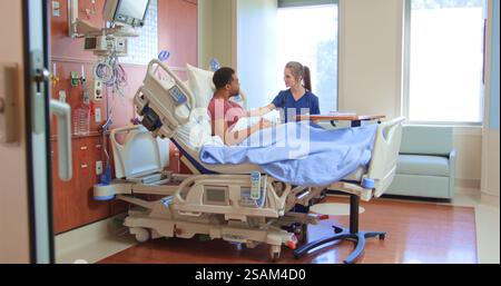 Infirmière féminine ou médecin avec stéthoscope parlant avec un patient masculin dans un lit d'hôpital privé Banque D'Images