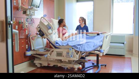 Infirmière féminine ou médecin avec stéthoscope parlant avec un patient masculin dans un lit d'hôpital privé Banque D'Images