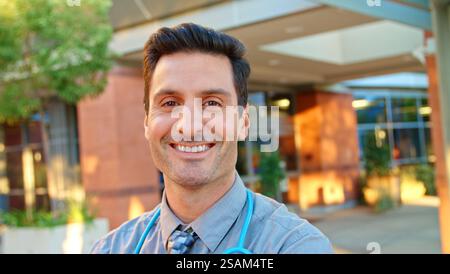 Portrait de médecin masculin avec stéthoscope au travail debout à l'extérieur de l'hôpital moderne Banque D'Images