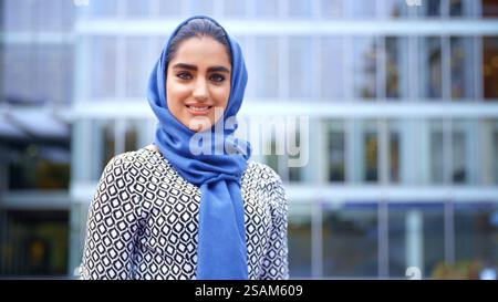 Portrait de jeune femme d'affaires musulmane britannique souriante portant le Hijab devant le bureau Banque D'Images