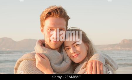 Tête et épaules Portrait d'un couple aimant serrant sur Winter Beach avec Golden Light Banque D'Images