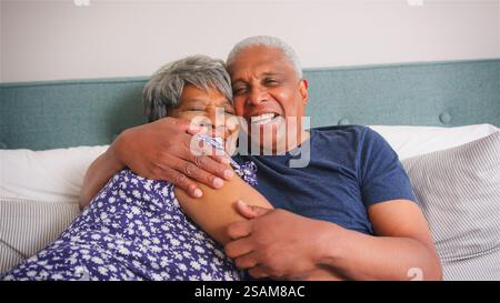 Couple senior aimant à la maison Cuddling dans le lit le matin Banque D'Images