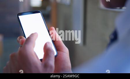 Au-dessus de l'épaule gros plan de l'homme d'affaires à l'aide du téléphone portable à écran vierge Banque D'Images