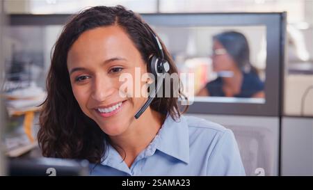 Agent d'équipe de télévente ou d'assistance clientèle féminin dans un bureau moderne portant un casque Banque D'Images