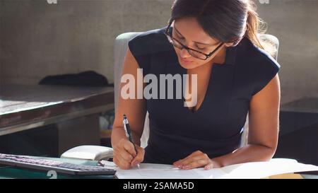 Gros plan de femme d'affaires portant des lunettes assis au bureau dans le bureau prendre des notes sur les fichiers de document Banque D'Images