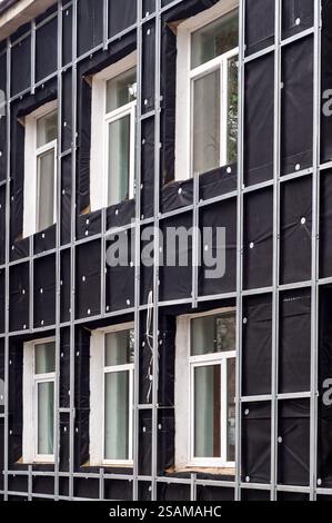 Vue détaillée de l'installation de l'isolation de façade avec des profils métalliques et membrane pare-vent, mettant en évidence les techniques de construction modernes. Banque D'Images