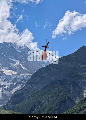 Un hélicoptère ambulance décolle pour une mission de sauvetage contre l'imposante toile de fond montagneuse des Alpes Banque D'Images
