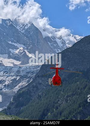 Un hélicoptère ambulance décolle pour une mission de sauvetage contre l'imposante toile de fond montagneuse des Alpes Banque D'Images