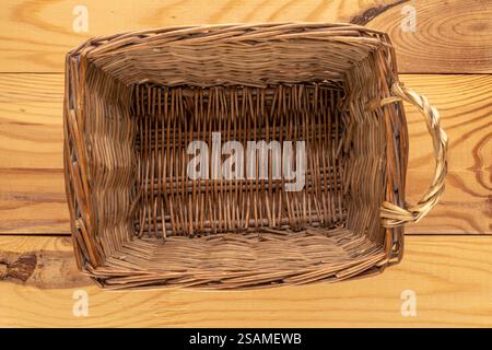 Un panier tissé à partir de branches d'arbre sur une table en bois, gros plan, vue de dessus. Banque D'Images