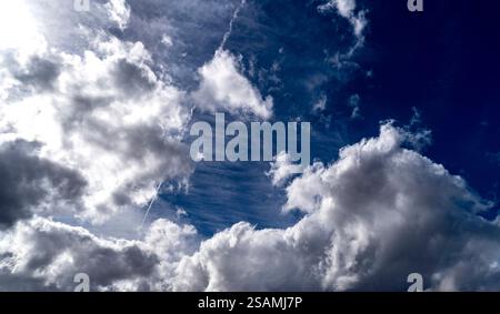 Un ciel spectaculaire rempli de nuages blancs moelleux sur fond bleu profond. Des nuages tordus et un léger effet de traînée ajoutent de la texture à la scène, créant un dy Banque D'Images