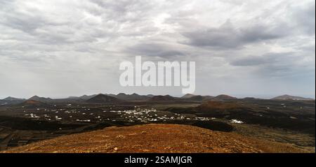 Une vue panoramique d'un paysage accidenté avec des collines ondulantes et des bâtiments blancs dispersés sous un ciel nuageux. Le terrain est pour la plupart aride avec des patchs Banque D'Images