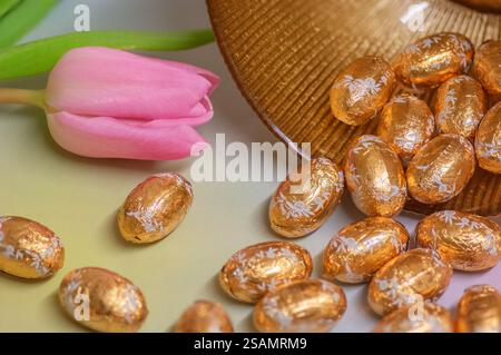 Oeufs de Pâques dorés et tulipes roses, gros plan ; joyeuses Pâques, fête de Pâques, fête du printemps. Banque D'Images