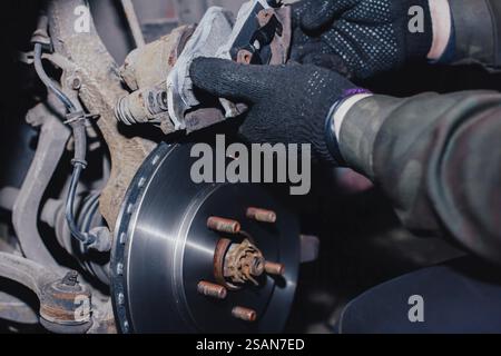 Mécanicien travaillant sur un système de freinage de voiture avec des gants Banque D'Images