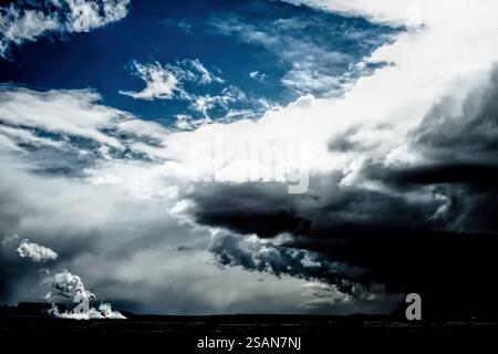 Le ciel est rempli de nuages sombres et de quelques nuages blancs. Les nuages sont dispersés dans le ciel, certains étant plus près du sol et d'autres hauts Banque D'Images