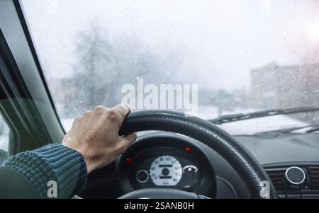 Volant de direction saisissant, regardant à travers un pare-brise moucheté par la pluie Banque D'Images