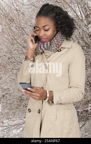 Belle femme qui parle des sms et le multitâche tout en jonglant avec les téléphones cellulaires et les conversations multiples Banque D'Images