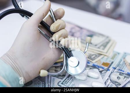 Main gantée tenant le stéthoscope au-dessus des billets d'un dollar, soulignant le lien économique et sanitaire Banque D'Images