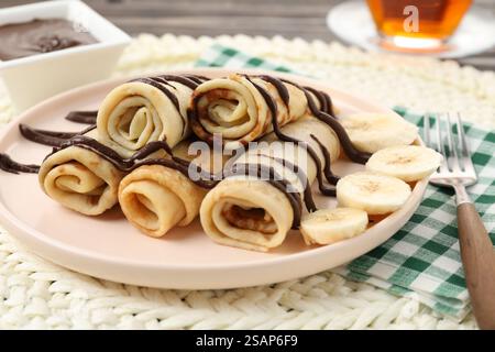 Délicieuses crêpes avec sauce chocolat et banane servies sur table, gros plan Banque D'Images