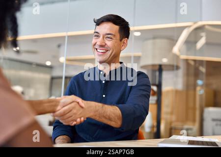 Heureux jeune homme d'affaires hispanique serrant la main client ou embauchant une personne au bureau. Banque D'Images