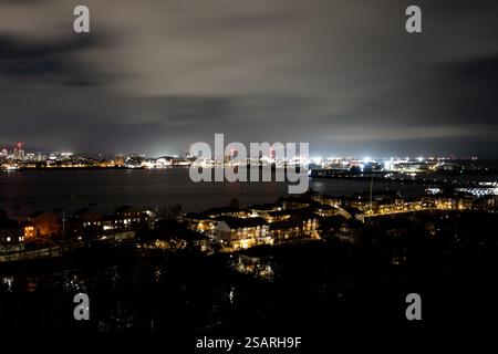 Vue aérienne nocturne du centre-ville de Cardiff avec ses lumières qui se reflètent sur la rivière Taff, avec l'emblématique Principality Stadium sous un ciel nuageux Banque D'Images