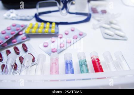 Rangée de tubes à essai colorés avec des pilules assorties en arrière-plan Banque D'Images