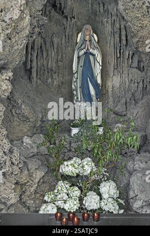 Figure de la Vierge Marie avec des décorations florales et des bougies sacrificielles dans la grotte de l'église paroissiale de St Laurentius, Koenigsdorf, Haut-Bava Banque D'Images