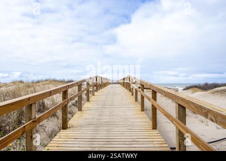 Promenade en bois invitante s'étendant vers une vue nuageuse sur la plage Banque D'Images