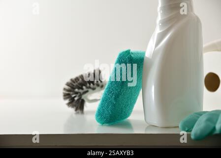 Détail du produit désinfectant et du tampon à récurer sur l'armoire en bois avec des gants éponge et du papier avec fond blanc isolé. Vue de face. Banque D'Images