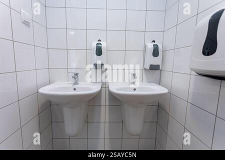 Toilettes publiques contemporaines avec plusieurs lavabos et désinfectants pour les mains disponibles Banque D'Images