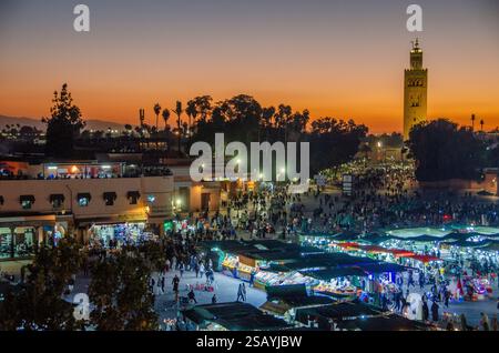 Étals de marché animés sur la place Jemaa el-Fnaa au coucher du soleil, mosquée Koutoubia en arrière-plan dans la médina, Marrakech, Maroc. Banque D'Images