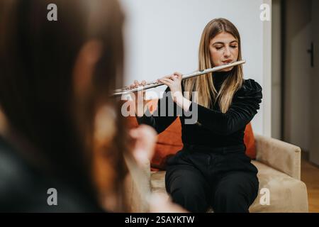 Jeune musicien jouant de la flûte lors d’une séance de pratique en intérieur Banque D'Images