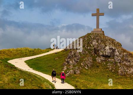 Touristes explorant le paysage vallonné avec croix à Ynys Llanddwyn une petite île au large de la côte d'Anglesey dans le nord du pays de Galles Royaume-Uni. Banque D'Images
