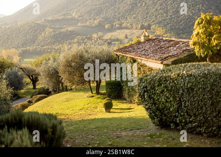 Un paysage toscan serein avec des maisons rustiques, une végétation luxuriante et des collines ondulantes sous la lumière douce du soleil. Une représentation parfaite du charme rural et de la beauté naturelle Banque D'Images