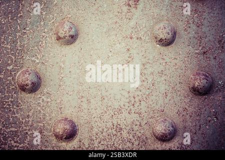 Une surface métallique avec un trou au centre et quatre trous l'entourant. Les trous sont tous de tailles différentes Banque D'Images