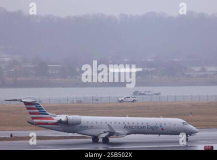 Un avion de passagers s'est écrasé avec un hélicoptère Black Hawk de l'armée à Arlington, va Un avion atterrit alors que les équipes de récupération fouillent l'épave d'un avion d'American Airlines sur le fleuve Potomac près de l'aéroport national Ronald Reagan Washington l'aéroport par une journée pluvieuse et venteuse le 31 janvier 2025 à Arlington, Virginie. L'American Eagle Flight, transportant 60 passagers et quatre membres d'équipage, est entré en collision avec un hélicoptère Black Hawk de l'armée américaine transportant trois membres des services américains au-dessus du fleuve Potomac près de l'aéroport national Reagan Washington tard le 29 janvier 2025. Washington DC USA Copyright : xMatrixxImagesx/xGentxShkulla Banque D'Images