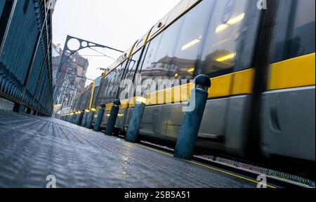 Un métro jaune circule sur l'emblématique pont Dom Luis I à Porto, Portugal, avec un bâtiment en arrière-plan. Entraînez-vous en mouvement Banque D'Images