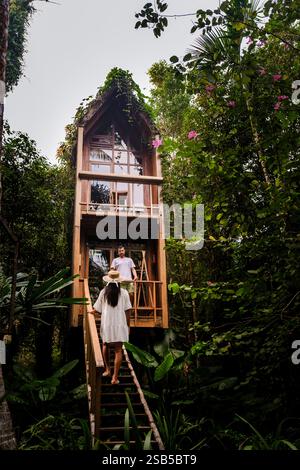 Nichée au cœur de la nature, une charmante cabane en bois invite à l'exploration. Entouré par un feuillage vibrant, deux aventuriers approchent, un couple prêt à embrasser la tranquillité et la beauté. Banque D'Images