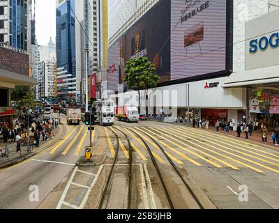 Hong Kong, Chine - 01 février 2025 : Un tramway de Hong Kong glisse le long de ses voies dédiées, flanqué de rues animées, de bâtiments imposants et de pédest Banque D'Images