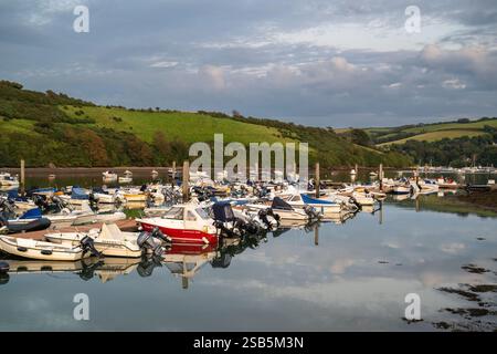 De petits bateaux ont mouillé sur une jetée au yacht club de Salcombe, avec des reflets dans l'eau très calme de Batson Creek le jour d'automne Banque D'Images