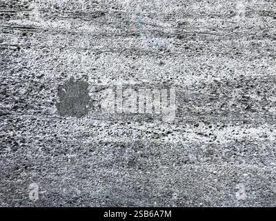 Mur gris et blanc avec un petit trou dedans. Le mur est rugueux et a beaucoup de texture Banque D'Images
