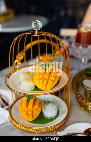 Une portion magnifiquement arrangée de riz collant à la mangue thaïlandaise avec des tranches de mangue fraîche, du riz gluant garni de haricots mungo et du lait de coco Banque D'Images
