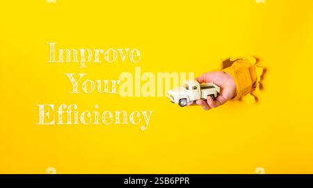 Main tenant un camion jouet avec les mots améliorer votre efficacité écrit ci-dessous. L'image a une ambiance ludique et légère, suggérant que le i. Banque D'Images