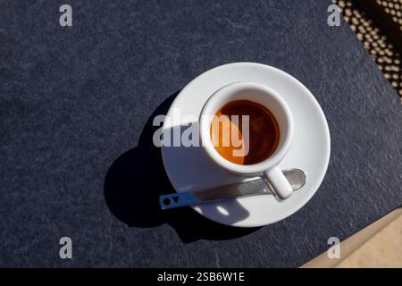 Une tasse d'espresso riche à la vapeur est posée sur une table grise lisse, offrant un moment parfait de simplicité et d'élégance. Le café noir contraste beau Banque D'Images