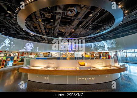 Exposition littéraire du African American History Museum Washington DC | WASHINGTON D.C., États-Unis — Une galerie incurvée dans l'exposition Carrefour musical du National Museum of African American History and culture expose des instruments, des sculptures et des portraits d'archives retraçant les réalisations musicales afro-américaines, ses images projetées comprenant un portrait de Billie Holiday. Les galeries culture du quatrième étage étudient les arts visuels, la performance et la musique, ainsi que l'exposition « Taking the Stage » sur l'histoire du divertissement. Banque D'Images