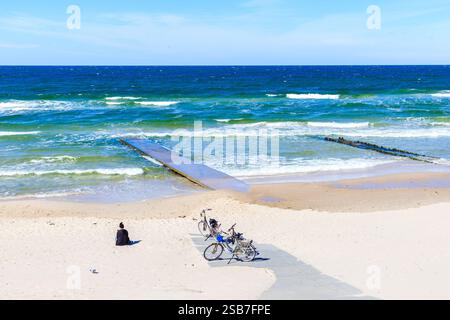 Femme touriste assise sur une belle plage de sable blanc près de Kolobrzeg et vélos garés à proximité, côte de la mer Baltique, Pologne Banque D'Images